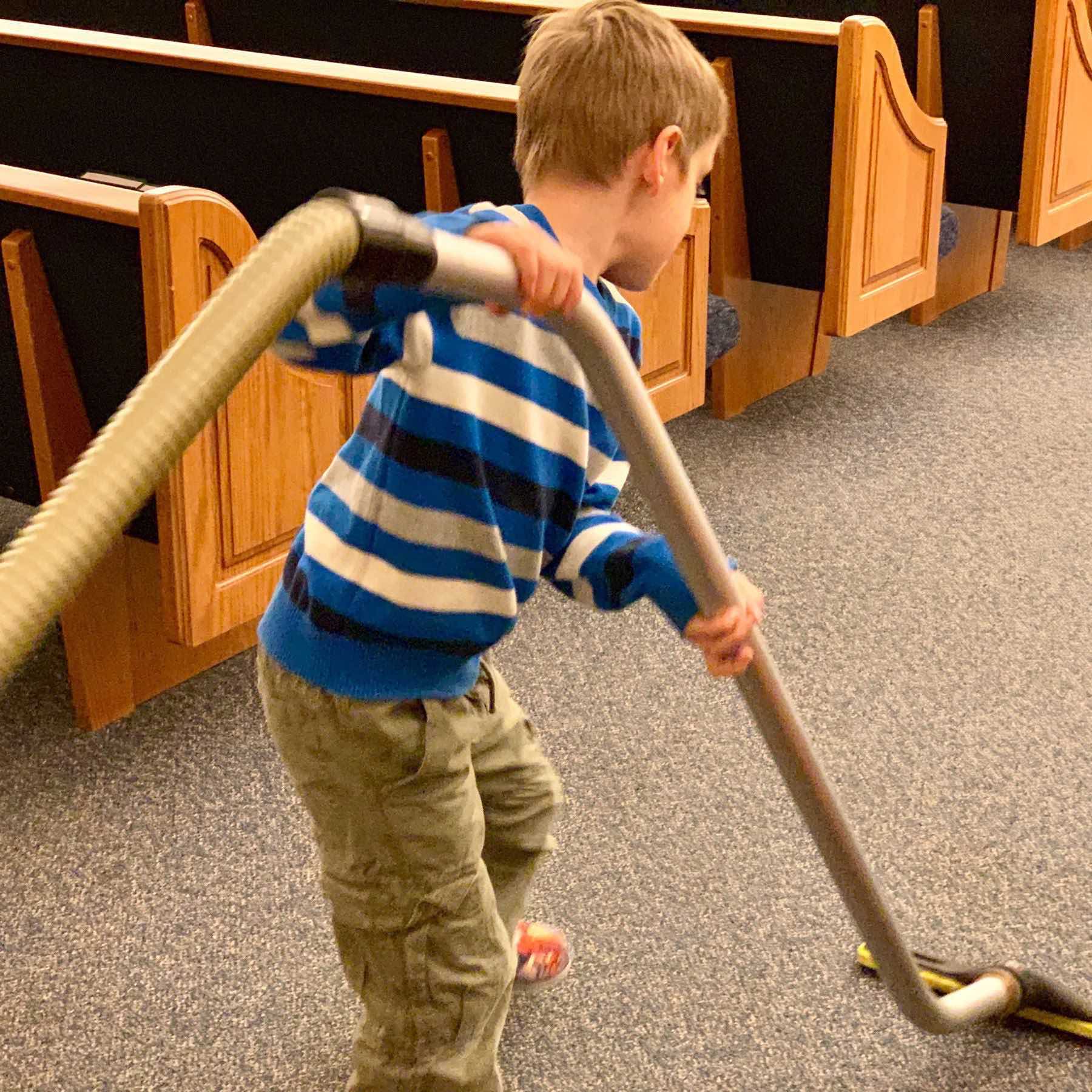 Six-year-old vacuuming the church